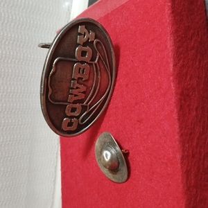 Cowboy buckle and cowboy hat pin.
